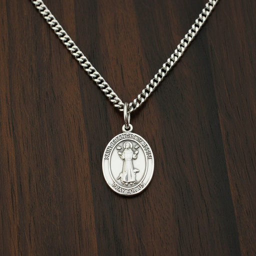 Silver medal of St. Francis of Assisi on a wood surface