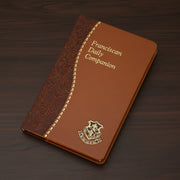 Brown faux leather book titled 'Franciscan Daily Companion' on a wood surface