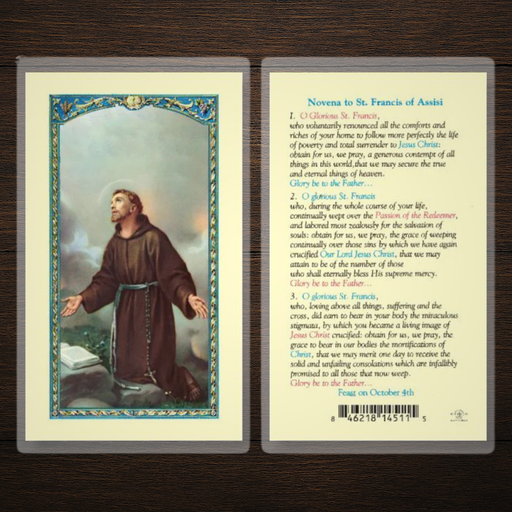 Prayer card with an illustration of a St. Francis of Assisi and text on a wooden surface