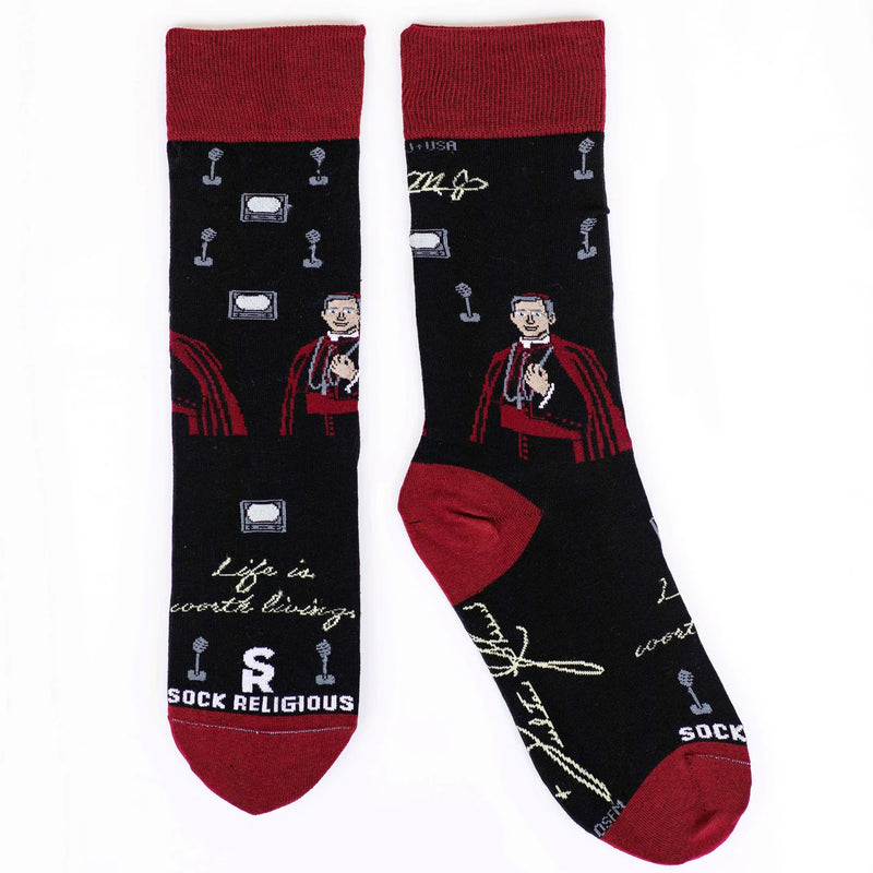 Person wearing black Fulton Sheen socks with red accents on a light gray pavement.
