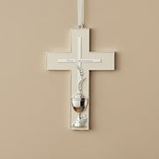 Decorative cross with chalice design on a beige wall, pointing towards 'First Communion'.