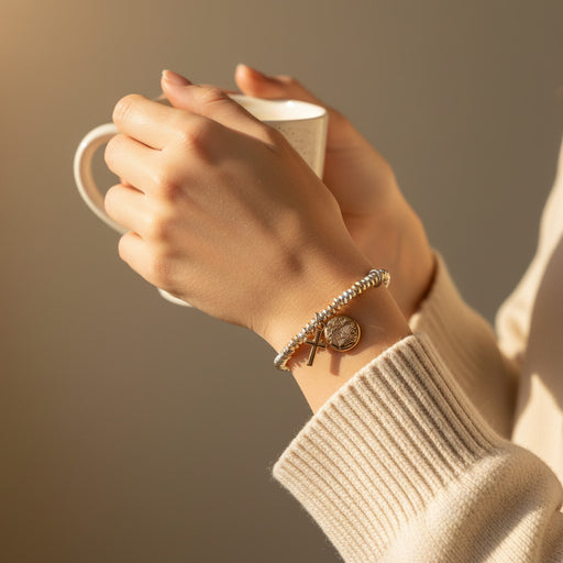 Hand holding a mug with a wrist wearing a bracelet against a warm background