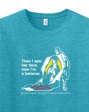Blue t-shirt with white graphic of Our Lady of Guadalupe and text reading 'Then I saw her face, now I'm a believer' on a white background