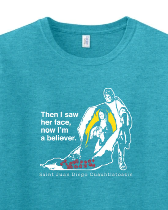 Blue t-shirt with white graphic of Our Lady of Guadalupe and text reading 'Then I saw her face, now I'm a believer' on a white background