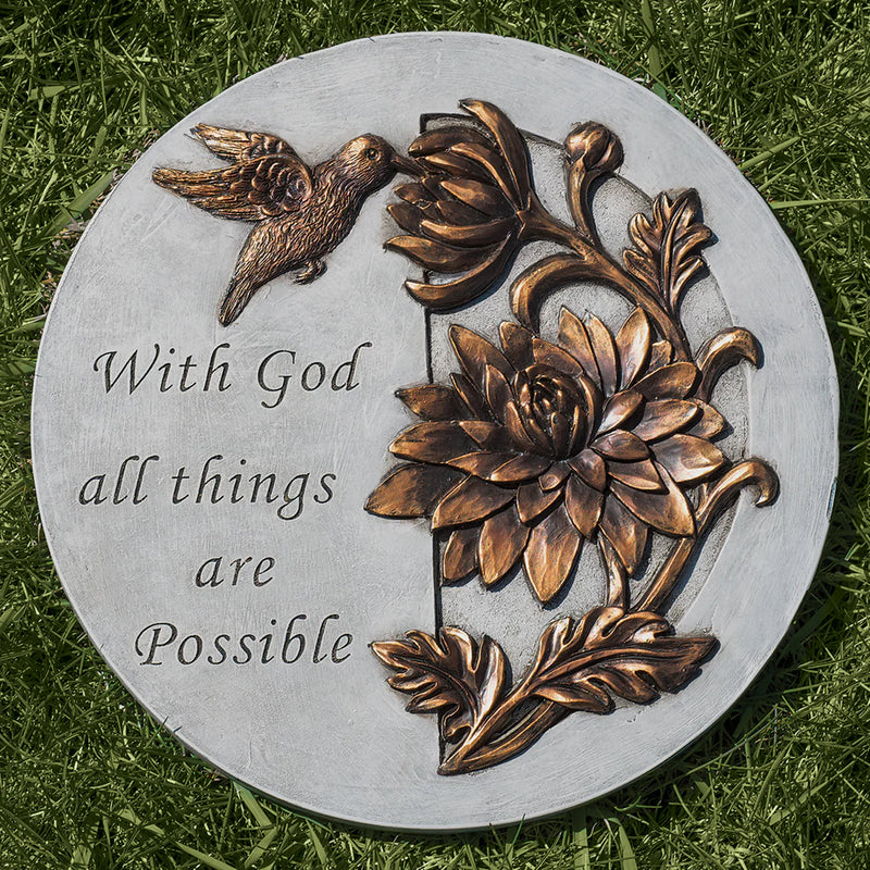 Decorative stone with floral design and 'With God all things are Possible' text on grass