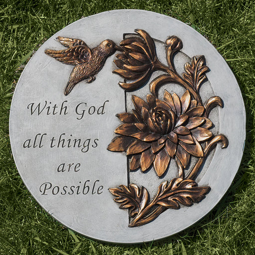 Decorative stone with floral design and 'With God all things are Possible' text on grass