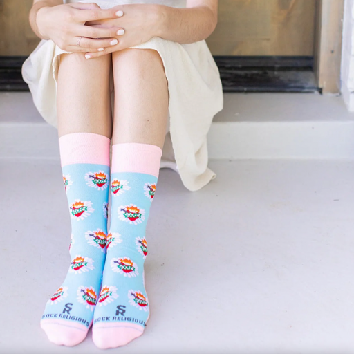 Person wearing pastel pink and blue socks with images of the Immaculate Heart of Mary