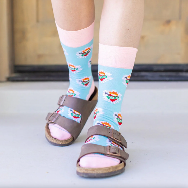 Person wearing pastel pink and blue socks with images of the Immaculate Heart of Mary
