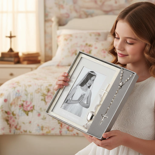 Young girl holding a boxed picture frame for a 4x6 inch photo and a rosary in a bedroom setting