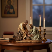 Statue of Jesus washing His Apostle's feet on a wood table in a dimly lit room.