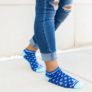 Person wearing blue St. Joan of Arc socks with a fleur-de-lis print