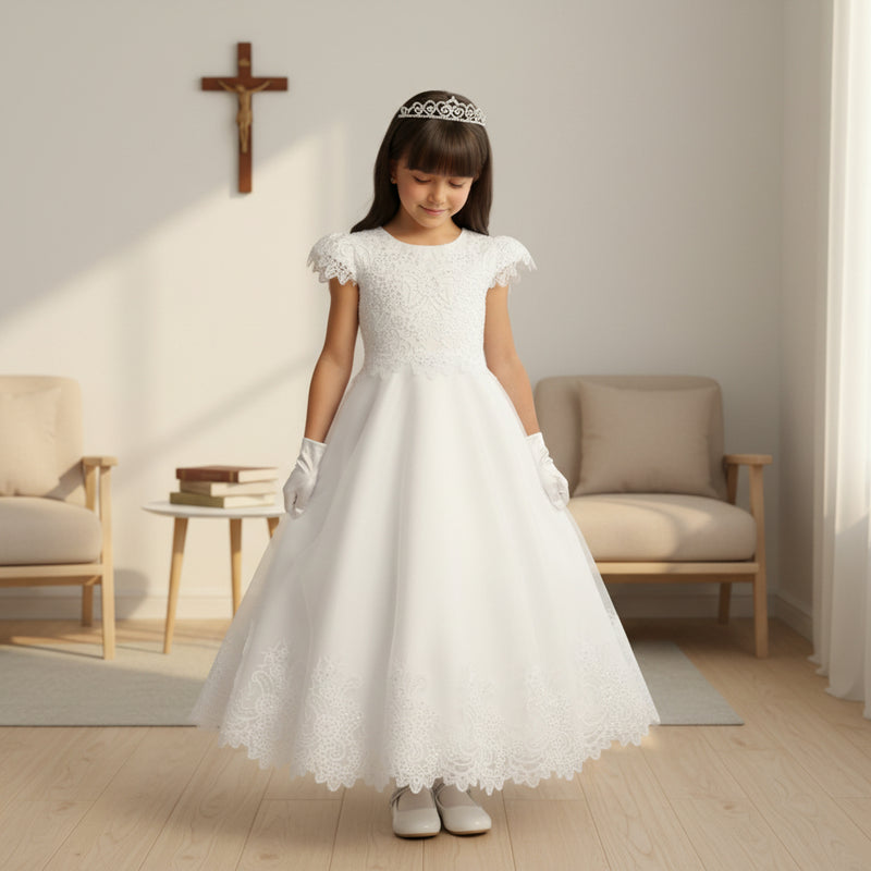Young girl in a white lace First Communion dress with a tiara in a softly lit room.