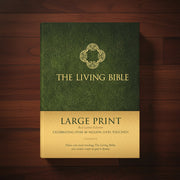 Green book titled 'The Living Bible' with gold text on a wooden surface