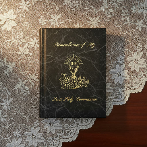 Black book titled 'Remembrance of My First Holy Communion' on a lace tablecloth