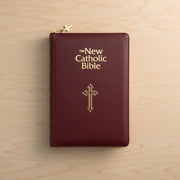 Maroon Bible with gold cross and text on a wooden surface