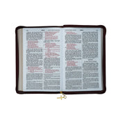 Bible with a maroon cover and gold cross charm on a white background
