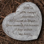 Heart-shaped memorial stone with engraved text on a bed of wood chips