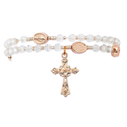 Rose gold rosary bracelet with clear beads and a cross pendant on a white background