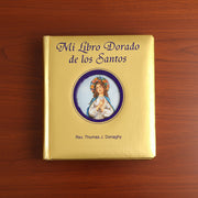 Gold book titled 'Mi Libro Dorado de los Santos' on a wooden surface
