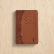 Brown leather book with 'My Daily Spiritual Companion' text on a wooden surface