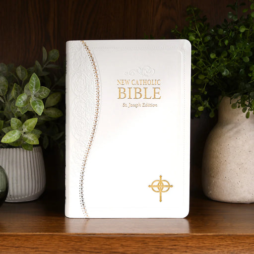 White Bible with gold text on a wood shelf