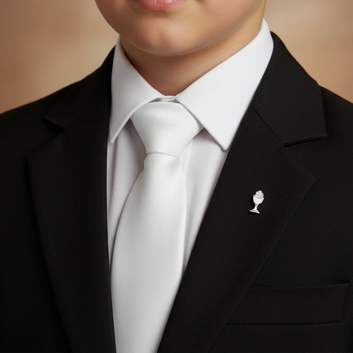 First Communicant boy wearing a black suit with a white shirt and tie, featuring a small decorative pin on the lapel.