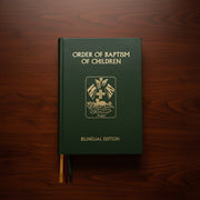 Green book titled 'Order of Baptism of Children' on a wooden surface
