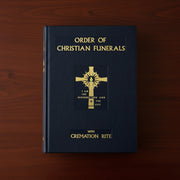 Book titled 'Order of Christian Funerals' with a gold cross on a wooden background