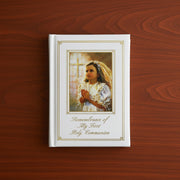 Book titled 'Remembrance of My First Holy Communion' with a portrait of a young girl on a wooden surface