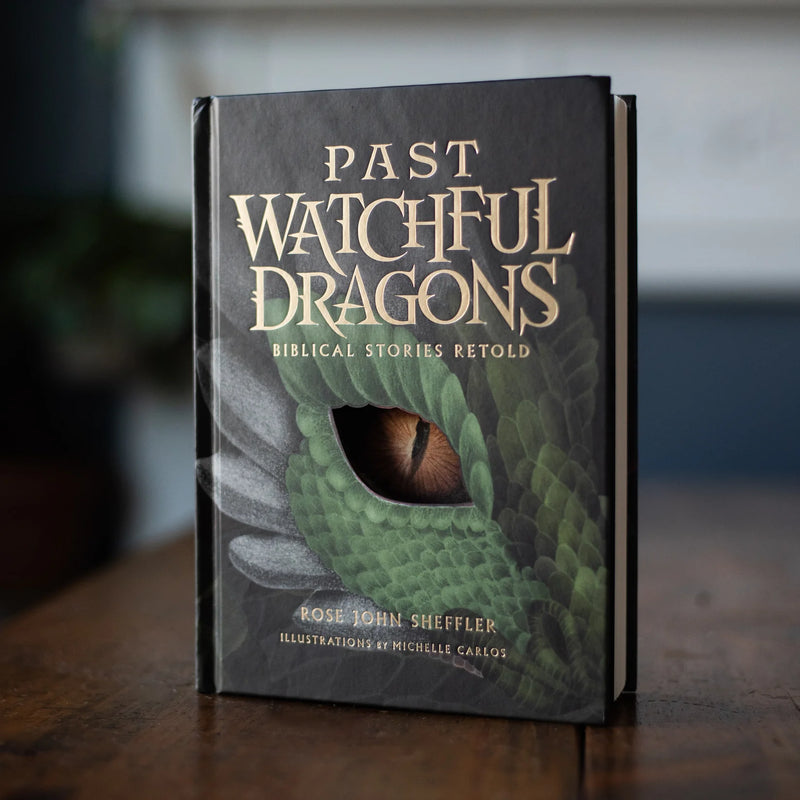 Book titled 'Past Watchful Dragons' with a dragon eye illustration on a wooden surface.