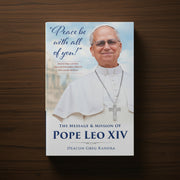 White and blue book with an image of Pope Leo XIV and the text 'Peace Be with You All' on a dark wood surface