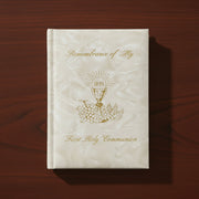 White pearlized Communion book with gold text and design on a wooden surface