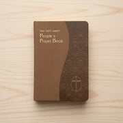 Brown prayer book with gold edges and a cross emblem on a white background