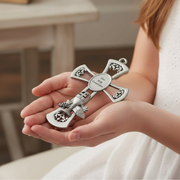 Young girl holding a metal First Communion gift cross with a chalice emblem in her hands.