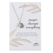 Necklace with prayer box pendant on a card with leaf designs and text.