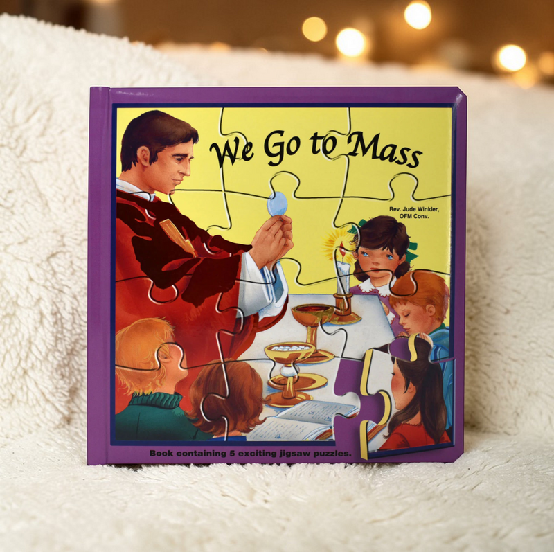 Jigsaw puzzle box titled 'We Go to Mass' on a soft surface with blurred lights in the background.