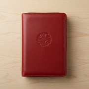 Red leather book cover with a logo on a wooden surface