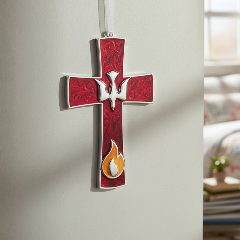Red Confirmation gift cross with flame and dove design adjusted by a hand against a neutral wall