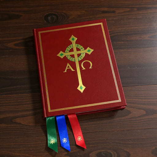 Red book with gold cross and symbols on a wooden surface