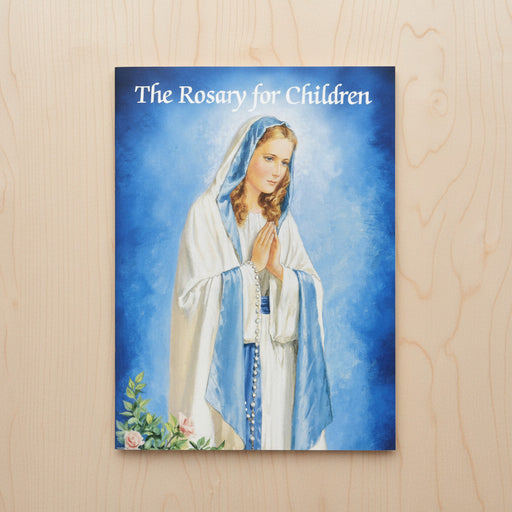 Booklet titled 'The Rosary for Children' with an illustration of a woman on a blue background, placed on a wooden surface.