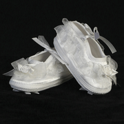 Pair of white baby booties with floral decorations on a black background