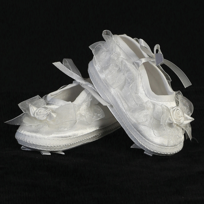 Pair of white baby booties with floral decorations on a black background