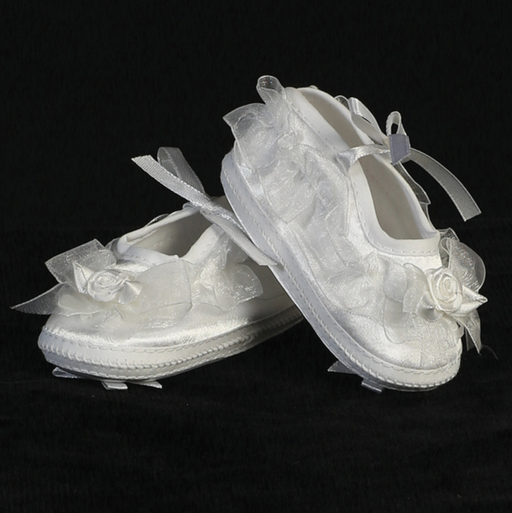 Pair of white baby booties with floral decorations on a black background