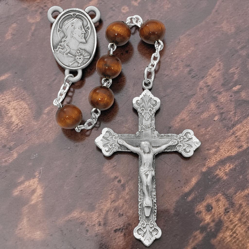 Silver rosary with brown beads on a wooden surface