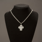 Silver chain necklace with a cross pendant on a black mannequin bust against a gray background