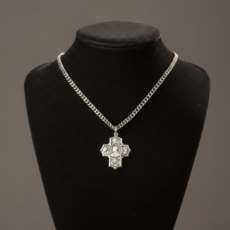 Silver chain necklace with a cross pendant on a black mannequin bust against a gray background