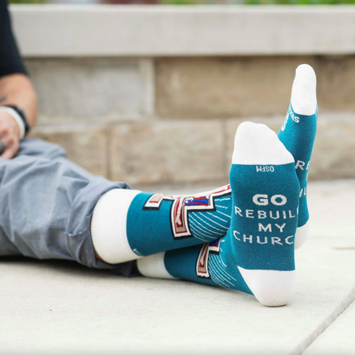 Person wear teal and white socks featuring an image of the Franciscan San Damiano crucifix
