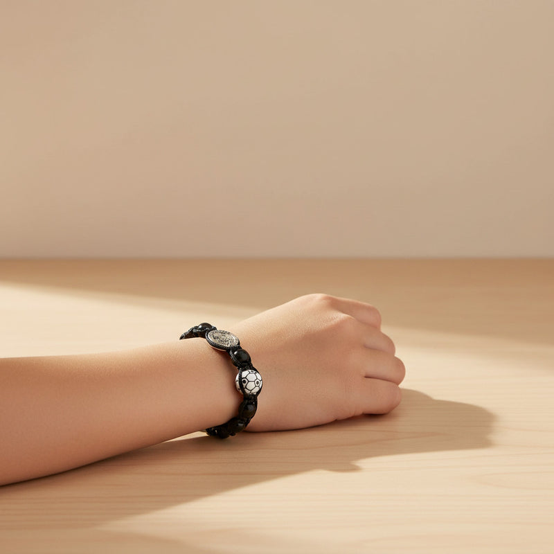 Hand wearing a black bracelet on a wooden surface with a beige background