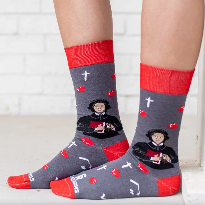 Person wearing red and gray sock featuring pictures of apples and St. Elizabeth Ann Seton