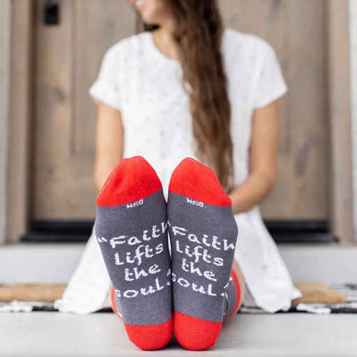Person wearing red and gray sock featuring pictures of apples and St. Elizabeth Ann Seton